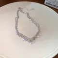 Detailed view of silver-toned necklace with sparkling zircon droplets on a white plate - Glittering Rhinestone Necklace / Silver