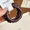 Close-up detail of a coffee brown pleated fabric scrunchie with elastic hair tie. - Dark Coffee