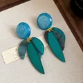 Gros plan de boucles d'oreilles tendance en résine marbrée bleue avec des feuilles turquoise - Bleu-Vert