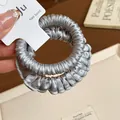 Detailed close-up of the elegant silver pleated satin texture on this elastic hair scrunchie. - Light Blue