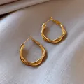 Elegant geometric twisted gold-finish hoop earrings for a minimalist and stylish look. - Twist Style (HE3791)