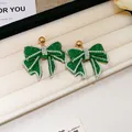 Elegant green resin bow stud earrings with rhinestone borders and gold-tone finish studs. - Green