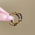Nahaufnahme von Retro-Creolen mit Leopardenmuster, handgehalten, zeigt Textur und Größe. - 52mm (8#) / Goldbraun
