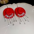 Rode cowboyhoed oorbellen met fonkelende strass kwastjes op een wit bord - Haakstijl / Rood
