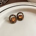 Detailaufnahme der geometrischen Leopard-Ohrstecker mit bernsteinfarbenen Kristallen im Retro-Stil - Leopardenmuster Kaffeebraun