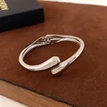 Vue détaillée d'un bracelet jonc argenté minimaliste en forme de goutte pour femme - Style ouvert en forme de larme / Argent