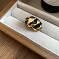 Nahaufnahme eines gold-schwarzen Emaille-Rings in einer Samt-Schmuckschale - Unregelmäßiger Offener Ring / Gold-Schwarz