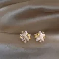 Close-up of star-shaped pearl stud earrings with gold accents and sparkling zircons - Gold (Silver Earring Post)