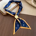 Close-up of retro navy paisley silk scarf necklace with a gold circular pendant buckle. - Blue Paisley