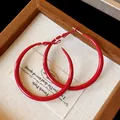 Detail shot of vintage red spray-painted hoop earrings on textured fabric background. - 5CM Diameter / Red