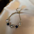 Elegant gold plated bracelet with sparkling blue and white crystals on silk background - Drawstring Adjustable Style / Gray