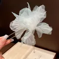 Close-up detail of an elegant light blue chiffon flower hair fork with a delicate pearl tassel - Green