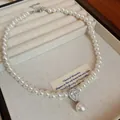 Macro detail of elegant pearl necklace with sparkling teardrop zircon pendant. - White