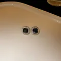 Close-up of elegant black square stud earrings with shimmering rhinestone halo - Black