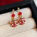 Detailansicht der roten Löwentanz-Emaille-Ohrringe mit Goldakzenten in einer Schmuckbox - 醒狮珠饰款式(款式一)