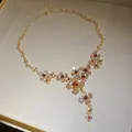 Detailed macro view of a vintage gold-tone necklace featuring elegant floral crystal motifs - Necklace (Floral Design) / Gold Brown