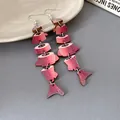 Dettaglio macro di orecchini a forma di pesce rosso in legno con stampa floreale etnica - Stile a Gancio / Rosso