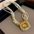 Detailed shot of vintage multi-strand pearl necklace with amber stone pendant - White-Gold