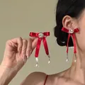 Primo piano di orecchini a fiocco rosso con strass eleganti e pendenti di perle bianche. - Orecchini (Fiocco a Pois Rosso)