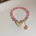 Detail of a pink cat-eye bead bracelet with a sparkling gold butterfly charm. - Butterfly Pendant Cat's Eye Bracelet / Pink