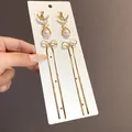 Dettaglio di eleganti orecchini a nappa con fiocco dorato, strass e perle raffinate - 7# Ago d'Argento - Oro