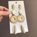 Primo piano di un elegante set di orecchini con perle e oro intrecciato su una scheda - 13# Perno in argento - Oro