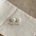 Dettaglio macro di eleganti orecchini di perle con accenti floreali in zircone su lino - Argento