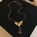 Detail of elegant gold plated clover flower tassel necklace on sleek black display base - 2# Flower Tassel Style / Gold