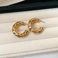 Detailed close-up of gold C-shaped chunky hoop earrings with a hammered textured finish. - Style 15 (HE28433) / Gold