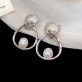 Primer plano detallado de los pendientes de aro anudados con perlas barrocas irregulares. - Estilo de aro / Plateado