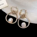 Vista macro de elegantes pendientes dorados con nudos y perlas centrales refinadas - Estilo de aro / Oro Café Claro