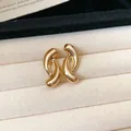 Close-up of minimalist gold twisted C-shape stud earrings on a velvet display tray - Style 7 / Gold