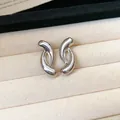 Detail of modern silver-tone curved earrings on a beige velvet jewelry tray. - Style 8 / Silver