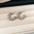 Detailed macro view of silver twisted croissant C-shaped hoop earrings on beige tray - Style 18 / Silver