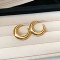 Detail view of chunky gold C-shaped hoop earrings resting in a beige jewelry box. - Style 3 / 3cm Slim / Gold