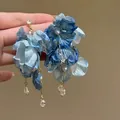Vista macro dettagliata di orecchini a fiore in tessuto blu con perle e cristalli fini - 7# (Perno in Argento)
