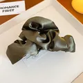 Primo piano di una molletta per capelli in raso verde oliva con eleganti pieghe alla francese - Verde