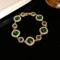 Elegante bracciale dorato con pietre verde smeraldo e dettagli in strass - Bracciale / Oro-Verde