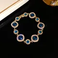 Elegante bracciale dorato con pietre preziose blu intenso e montatura a halo in cristallo - Bracciale / Oro-Blu