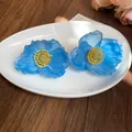 Primo piano dettagliato di eleganti orecchini a fiore in tessuto blu su piatto bianco - Stile 45 (Perno in Argento)