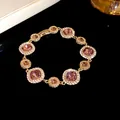 Vista dettagliata di un elegante bracciale dorato con pietre rosa scintillanti - Bracciale / Oro-Viola
