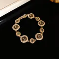 Dettaglio macro di bracciale dorato con gemme fumé e alone di cristalli - Bracciale / Oro-Grigio