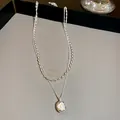 Macro detail of a double-layered necklace with a water-drop pearl pendant. - Double Layer Water Drop Pendant Necklace / Silver