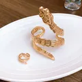 Detailed view of a golden titanium steel snake ring and matching bangle set. - Snake Bracelet And Ring Set / Gold