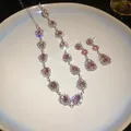 Detailed view of pink water drop rhinestone necklace and earrings on a white plate - Pink