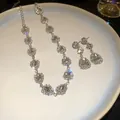 Close-up of elegant teardrop crystal jewelry set with sparkling rhinestone halo on a white plate. - Silver