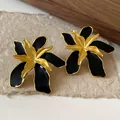 Close-up of vintage black enamel flower stud earrings with elegant gold metallic finish - Black