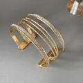Detail view of an elegant multi-layer gold open bangle with glitter finish for women. - Gold and Silver