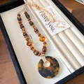 Detailed view of a retro wooden bead necklace with an elegant tortoiseshell pendant - Gold Brown