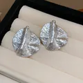 Macro view of irregular silver wrinkled geometric stud earrings in a display box. - Style 34 Hammered Texture Irregular Oval (Silver Earring Post) / Silver